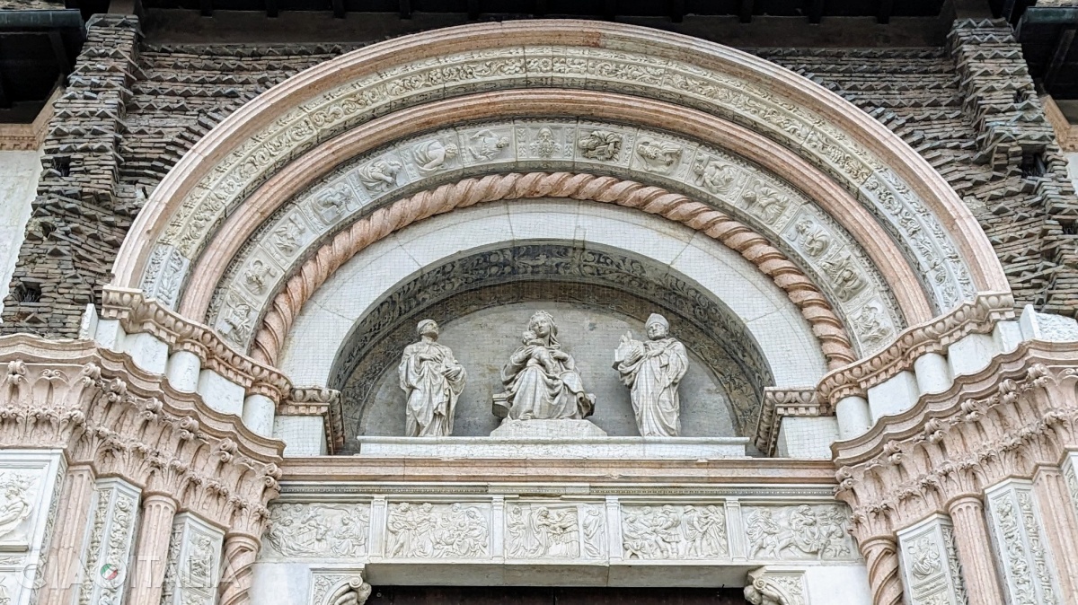 Statuile de deasupra portalului îi reprezintă pe Sf. Ambrozie, Fecioara Maria și Sf. Petroniu. Sub ele, cinci basoreliefuri înfățișează scene din Noul Testament.
