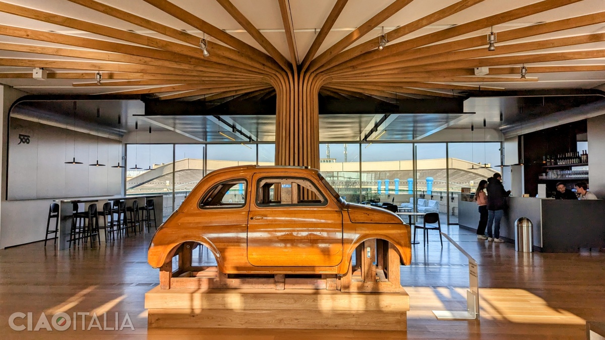 În centrul sălii, sub copacul realizat din lemn reciclat, se află modelul utilizat la caroseria mașinii Fiat 500 din anii '50.