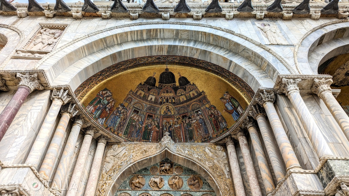 Cel mai vechi mozaic de pe fațada principală este cel din extremitatea stângă. Deasupra, în lojă, se văd cei patru cai, iar sub medalionul lui Iisus e reprezentat sicriul cu corpul Sf. Marcu.